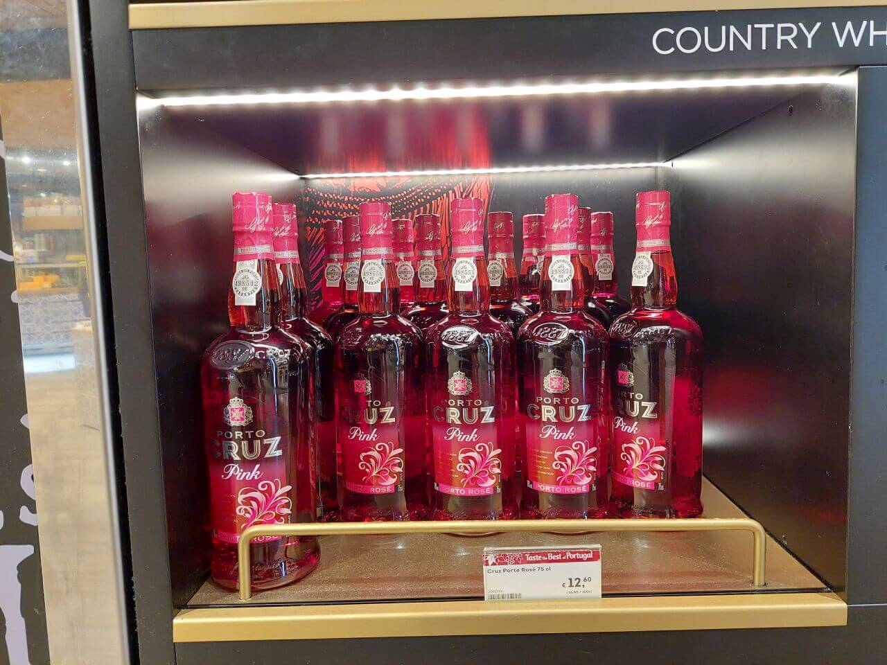 Láhve portského vína Porto Cruz Pink srovnané v regálu na letišti v Portu